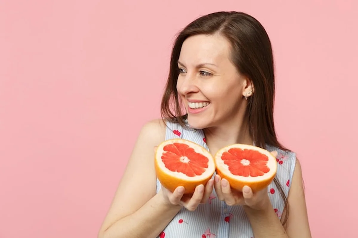 Młoda kobieta trzymająca grejpfruty na białym tle