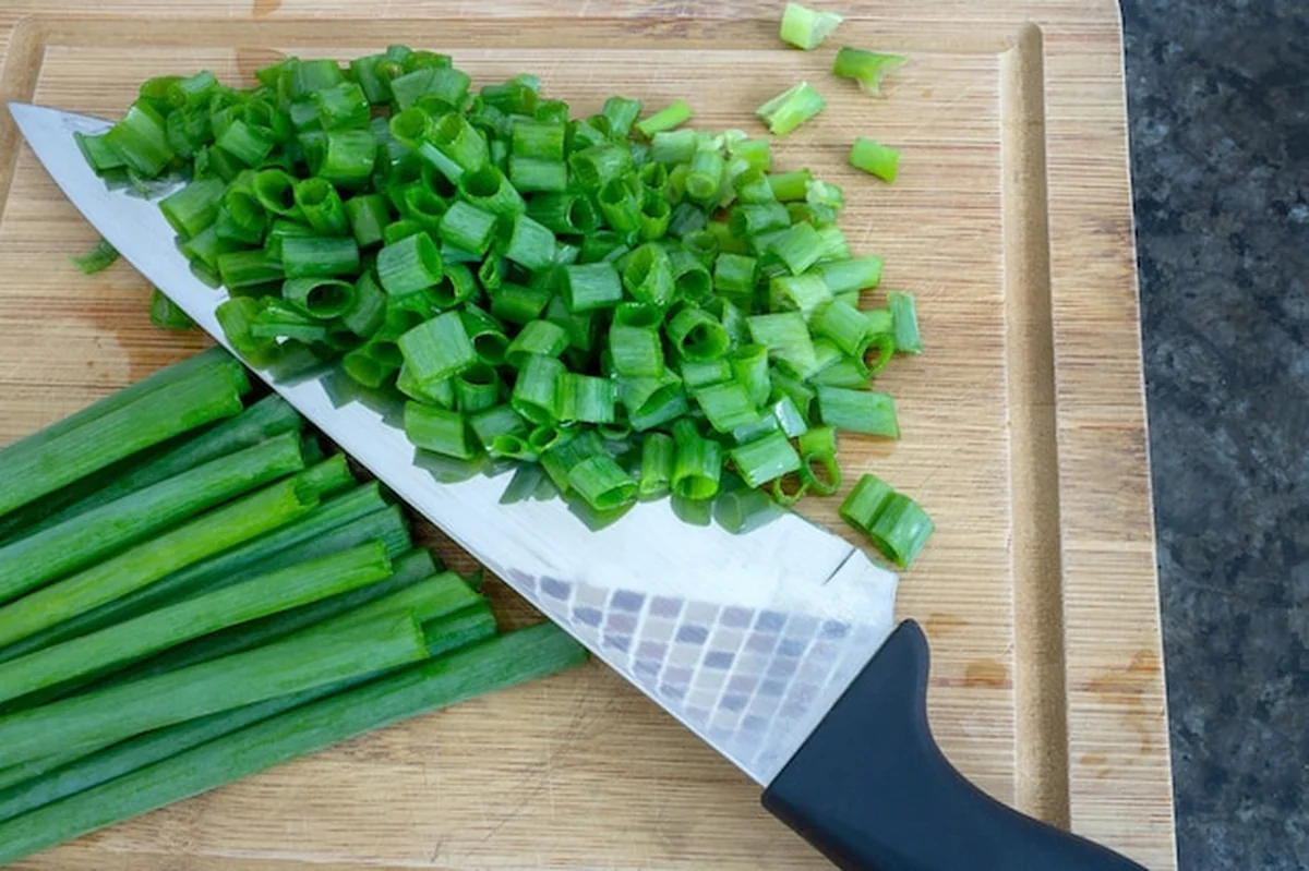 Szczypiorek w całości i pokrojony na drewnianej desce
