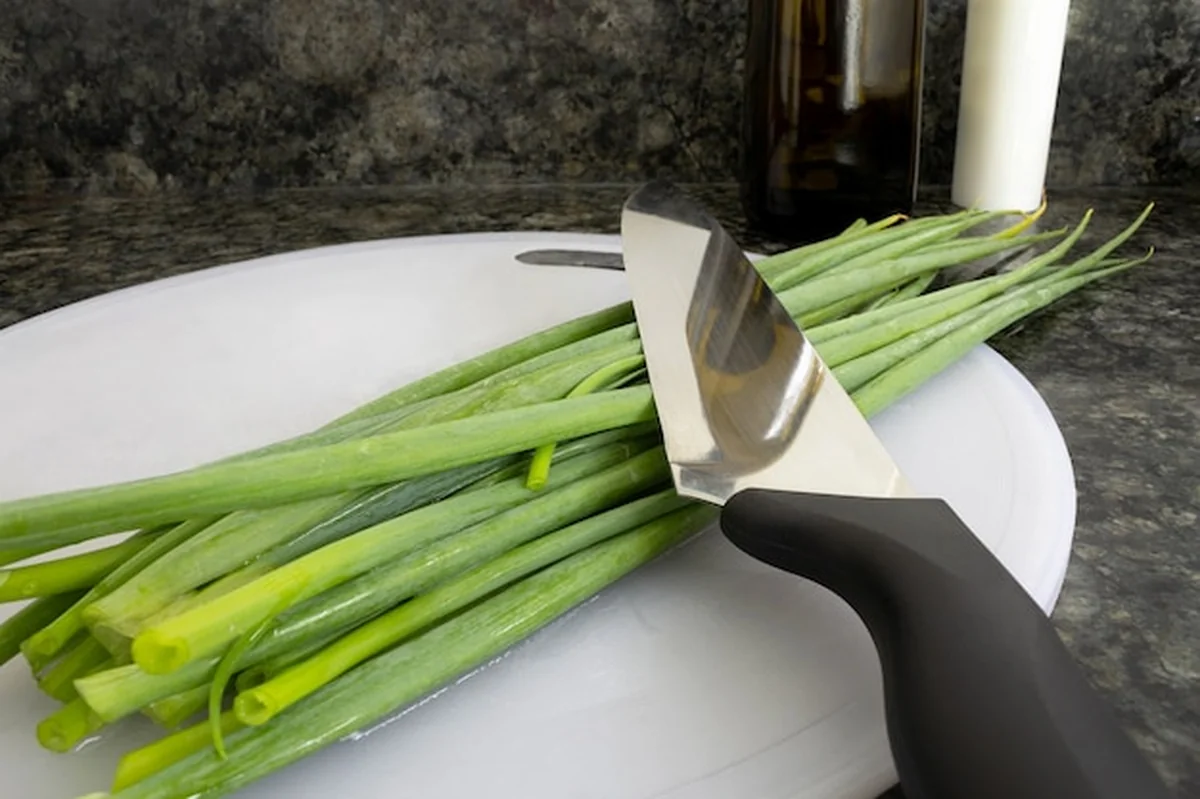 Cały szczypiorek na desce i nóż powyżej