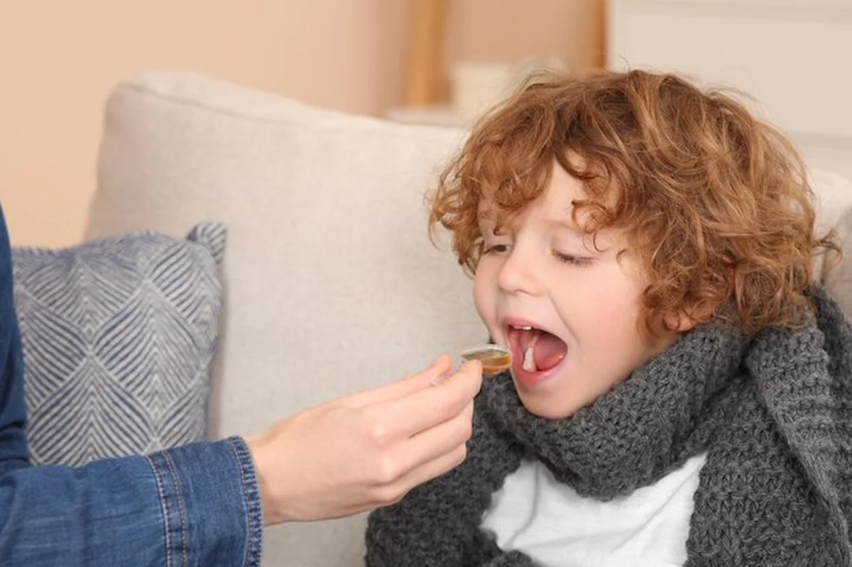 Matka daje syrop na kaszel synowi na kanapie