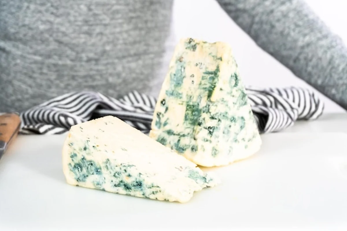 Duży kawałek sera pleśniowego na białej desce do krojenia