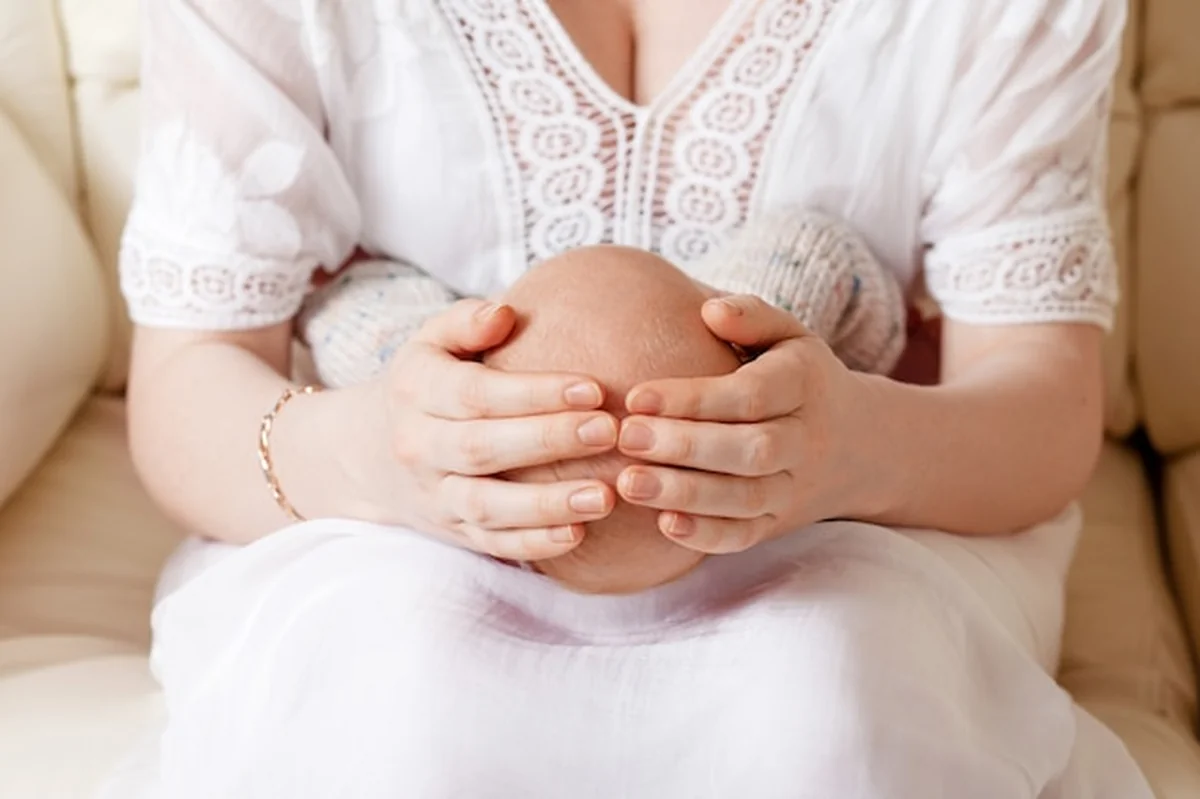 Kobieta trzymająca noworodka na rękach. Matczyna miłość w gestach