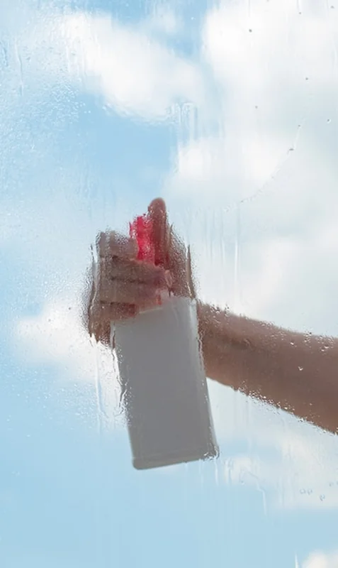 Ręka kobiety w sprayu do mycia okien na zewnątrz