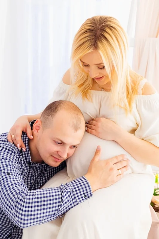 Ojciec dotyka ucha brzuchem żony, obraz przyszłych rodziców