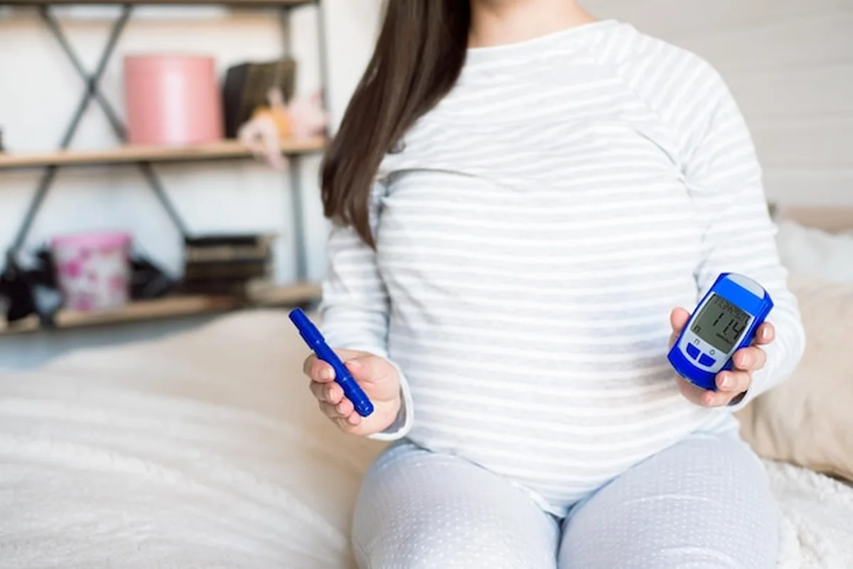 Kobieta w ciąży mierzy poziom cukru we krwi miernikiem glukozy