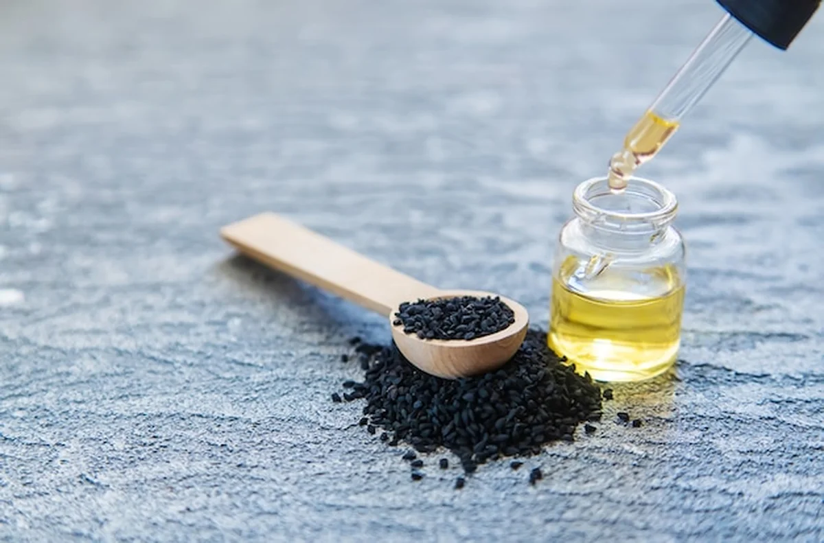 Olejek eteryczny z czarnuszki na tle natury i jedzenia