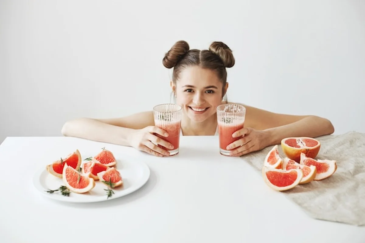 Kobieta siedząca przy stole z plasterkami grejpfruta