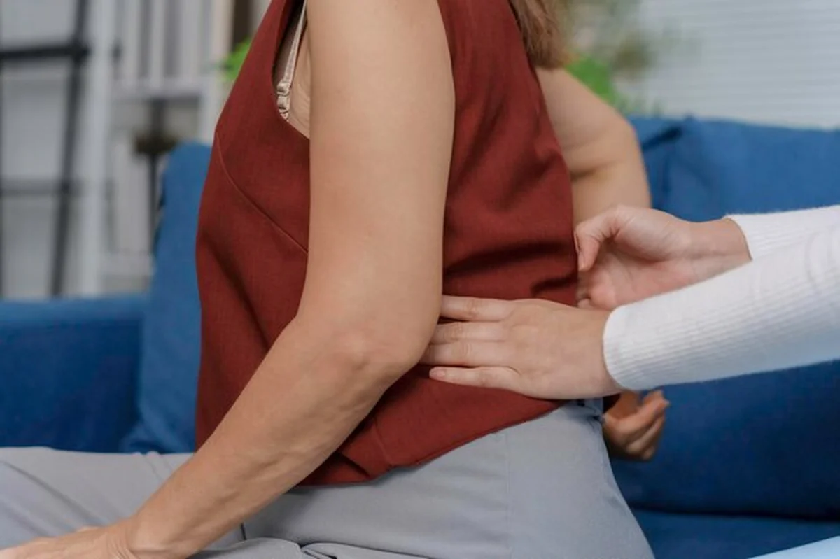 Lekarz bada dojrzałą kobietę z bólem pleców w domu