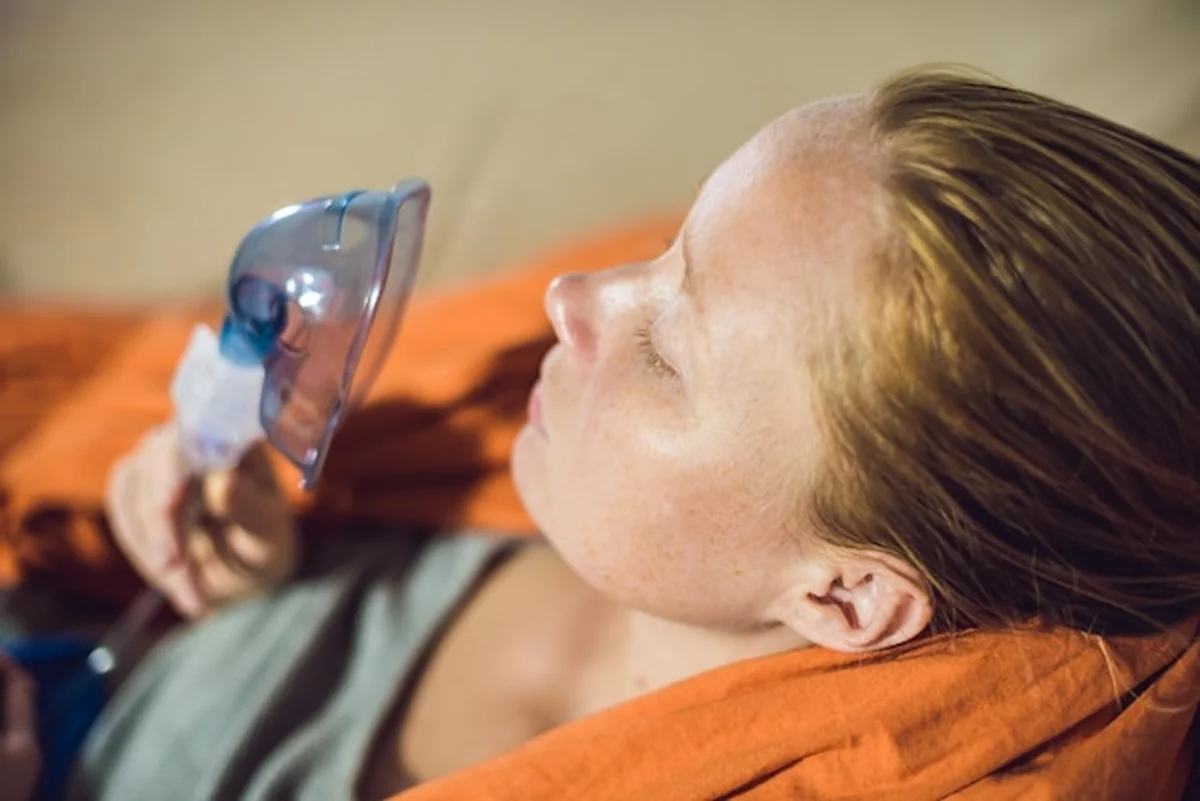 Kobieta inhalująca za pomocą nebulizatora w domu