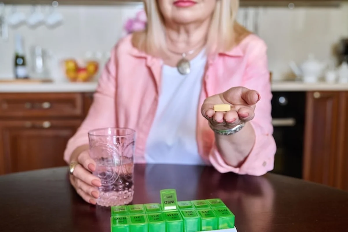 Starsza kobieta bierze witaminy z pudełka na pigułki