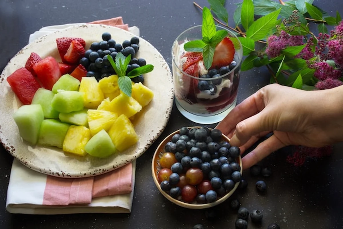 Talerz owoców: truskawki, jagody, ananas, arbuz i kantalupa na ciemnym tle