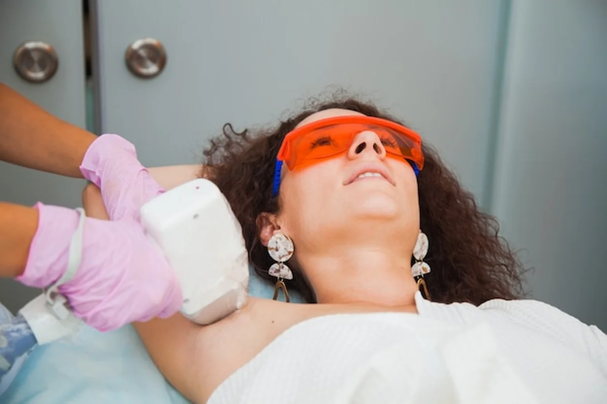 Młoda kobieta usuwa włosy na nogach w klinice kosmetologii