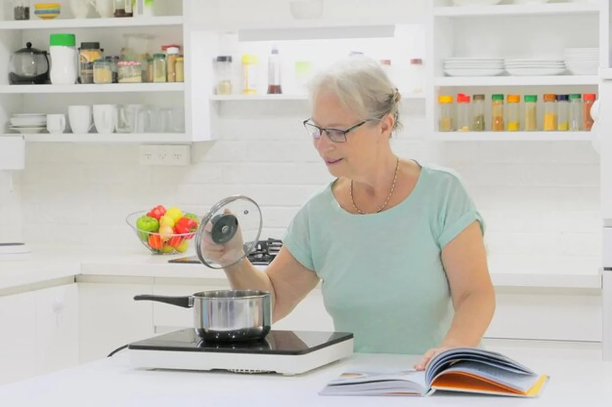 Starsza kobieta przygotowuje jedzenie w kuchni