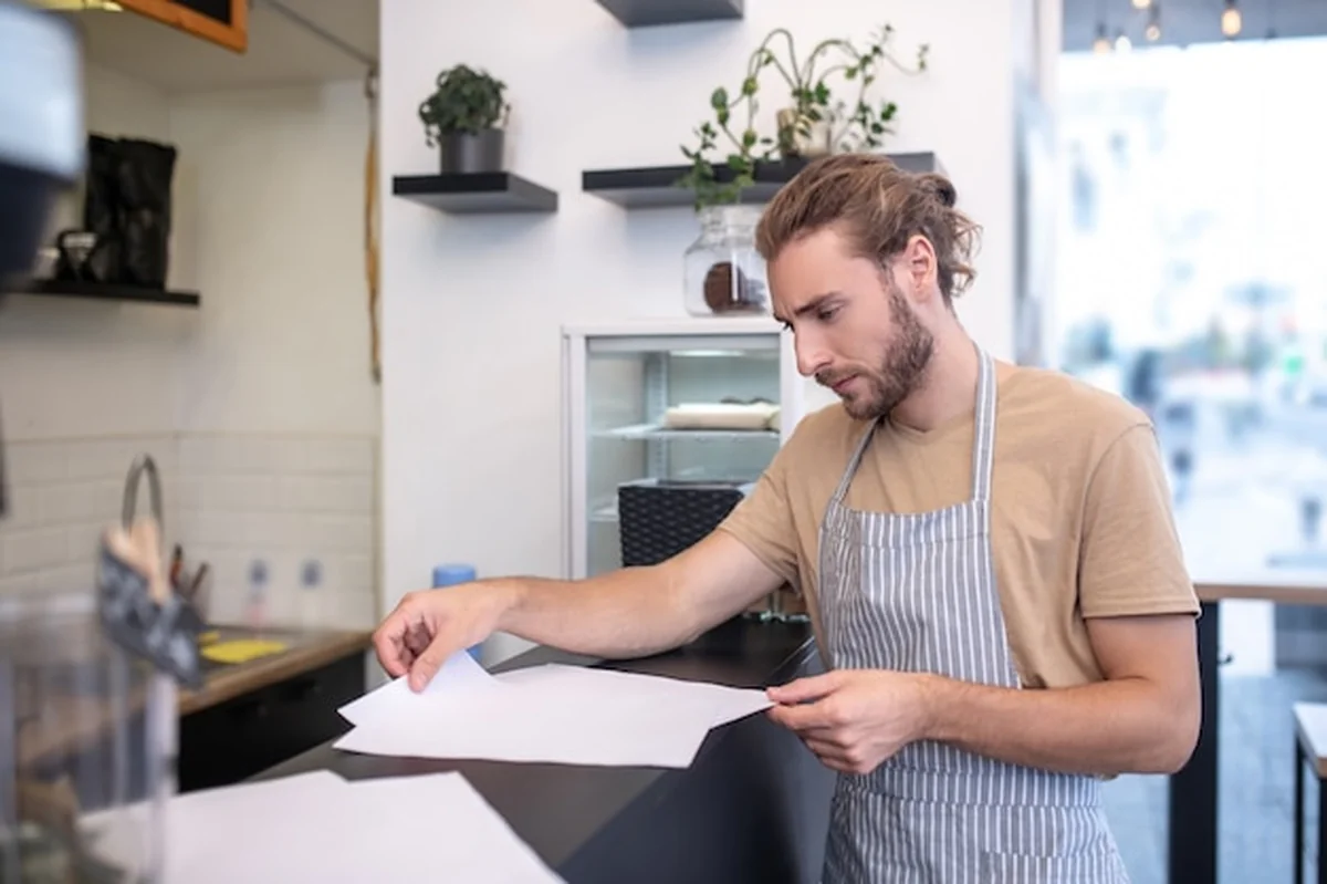 Mężczyzna w fartuchu analizuje dokumenty w kawiarni